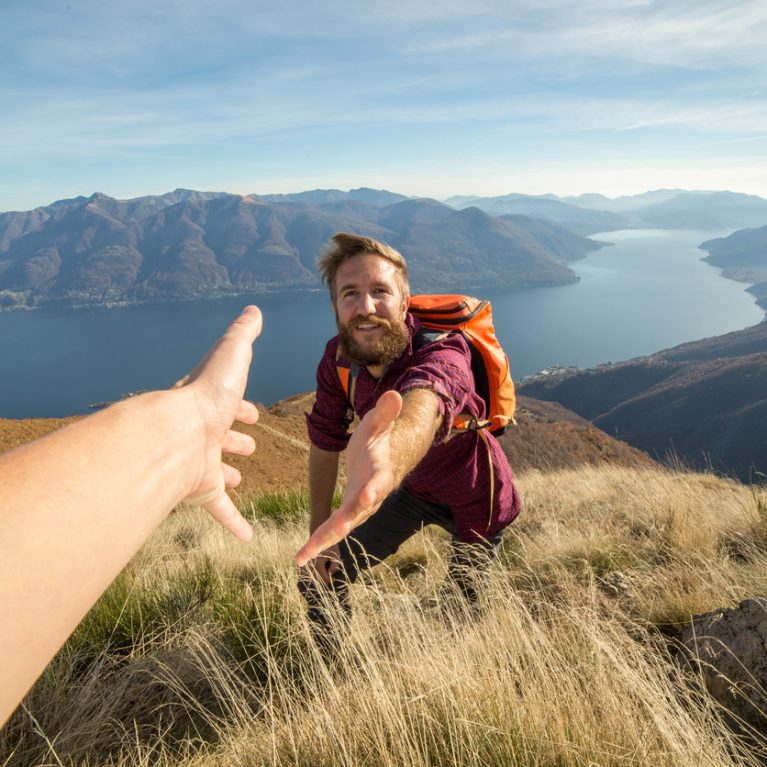 Young man hiking pulls out hand to get assistance